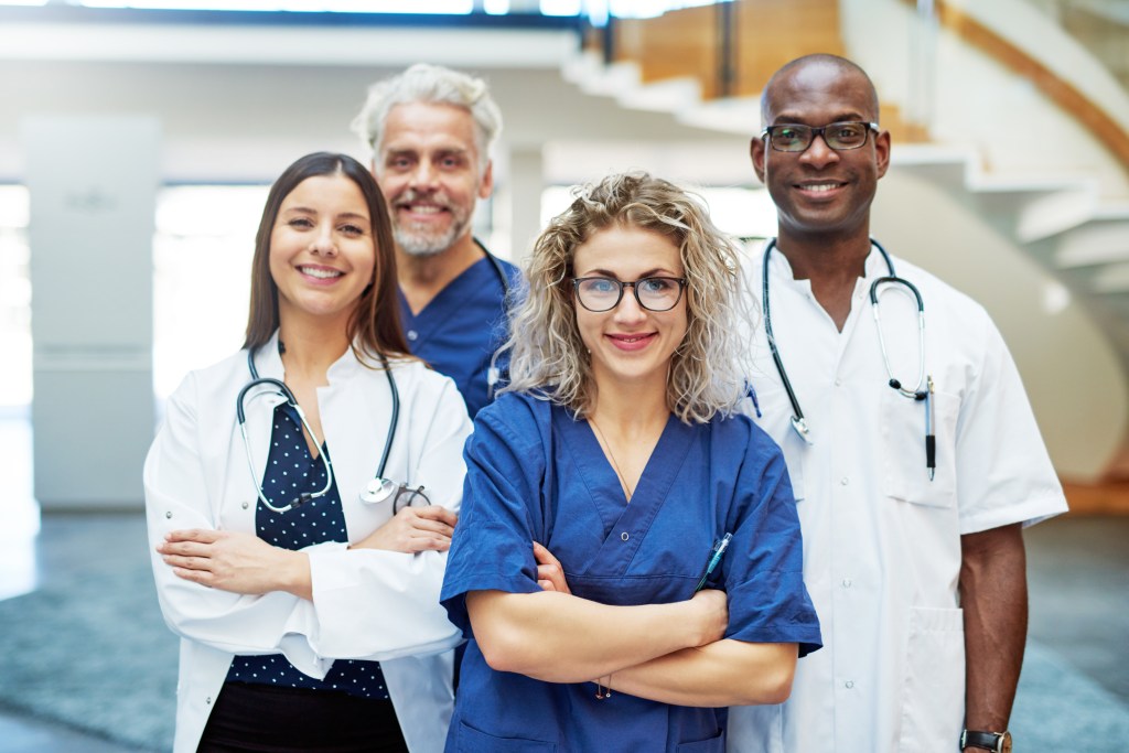 Smiling medical team with arms crossed standing in a clinic and looking at camera.