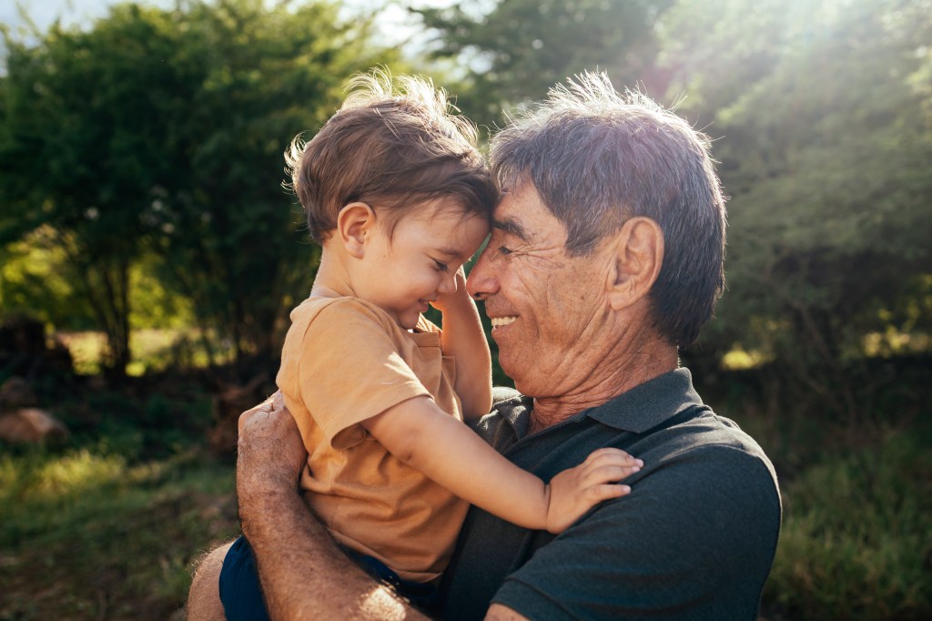 Grandfather spending time with his grandson in park on sunny day.