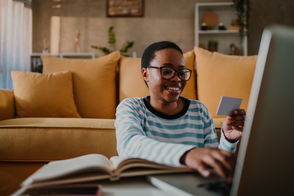 Woman using a credit card to online shop on her laptop at home.