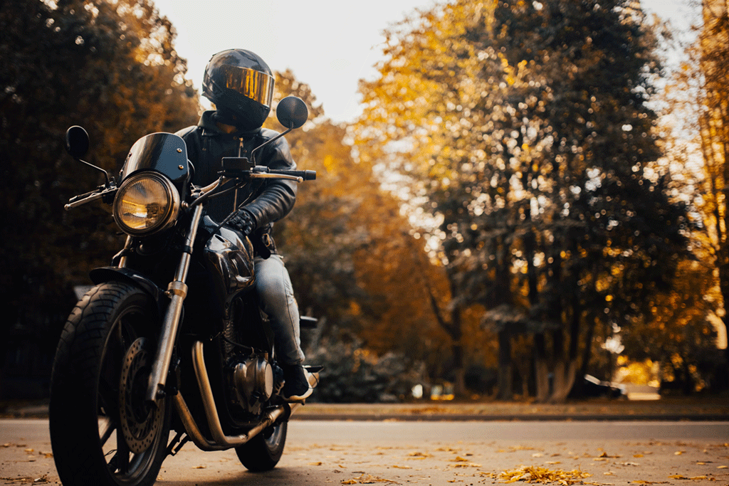 Motorcyclist in a helmet sitting on classic motorcycle in the fall.