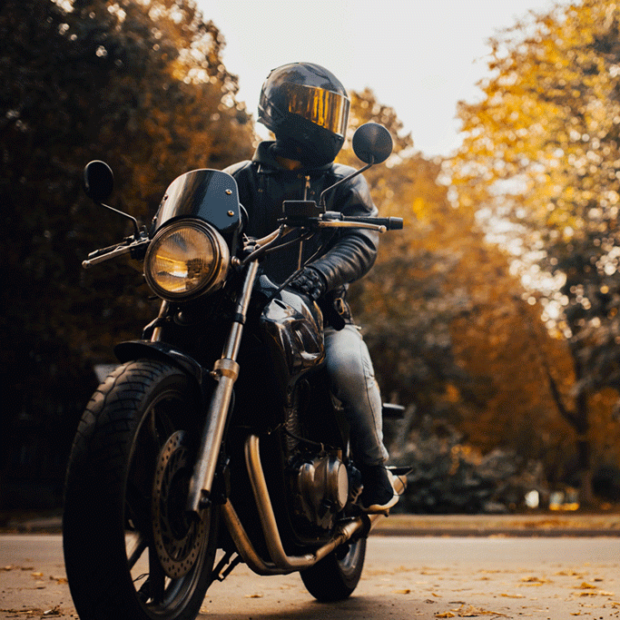 Motorcyclist in a helmet sitting on classic motorcycle in the fall.