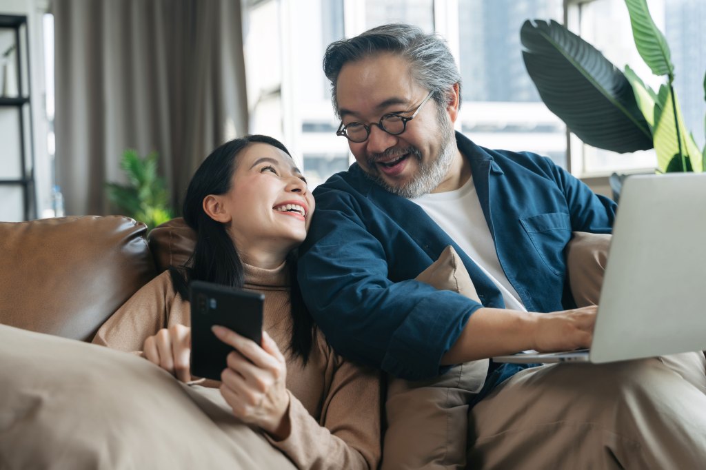 Female showing her smartphone to husband while sitting on the living room couch.