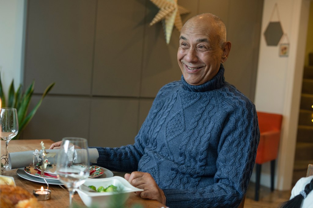 Senior man enjoys dinner with his family at the dining room table.