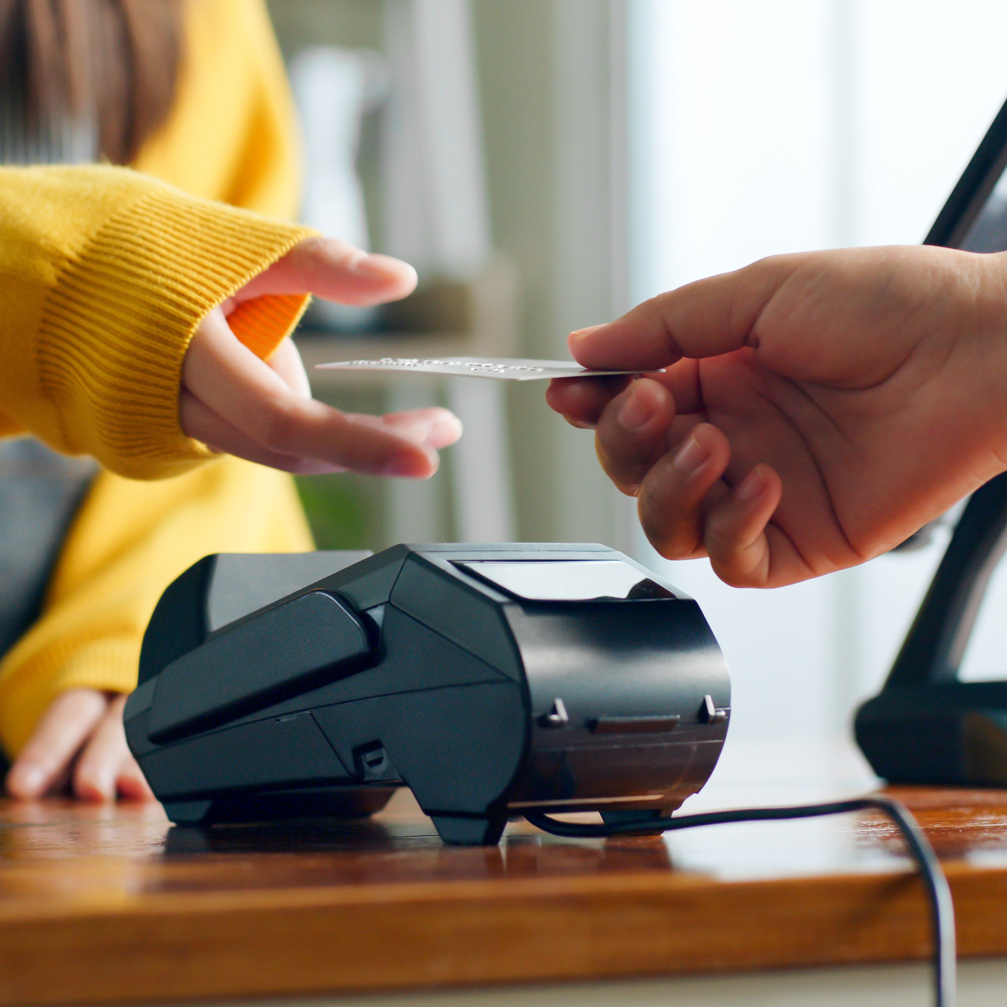 Customer hands credit card to worker at checkout terminal at cafe restaurant.